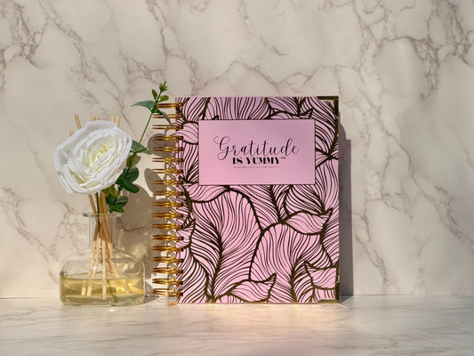 Gratitude is Yummy physical manifestation journal with pink and gold cover on a marble surface for subconscious mind rewiring