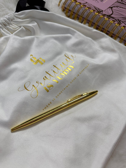 Gold pen on a white surface with 'Gratitude is Virtue' text