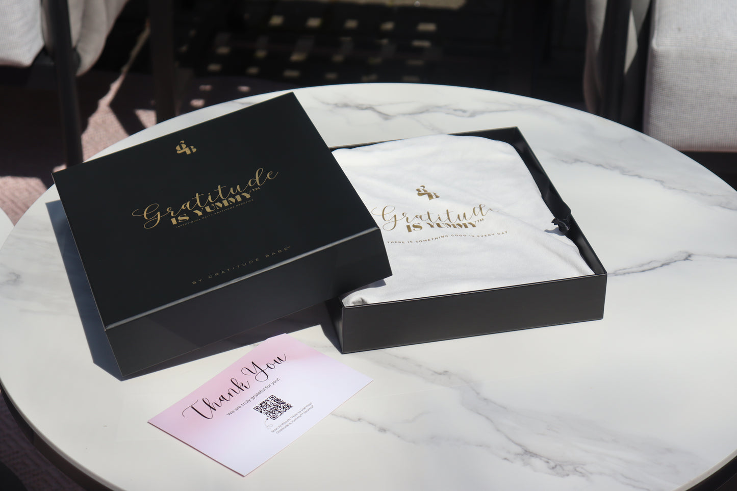 Open black gift box with 'Gratitude is Yummy' text on a marble surface