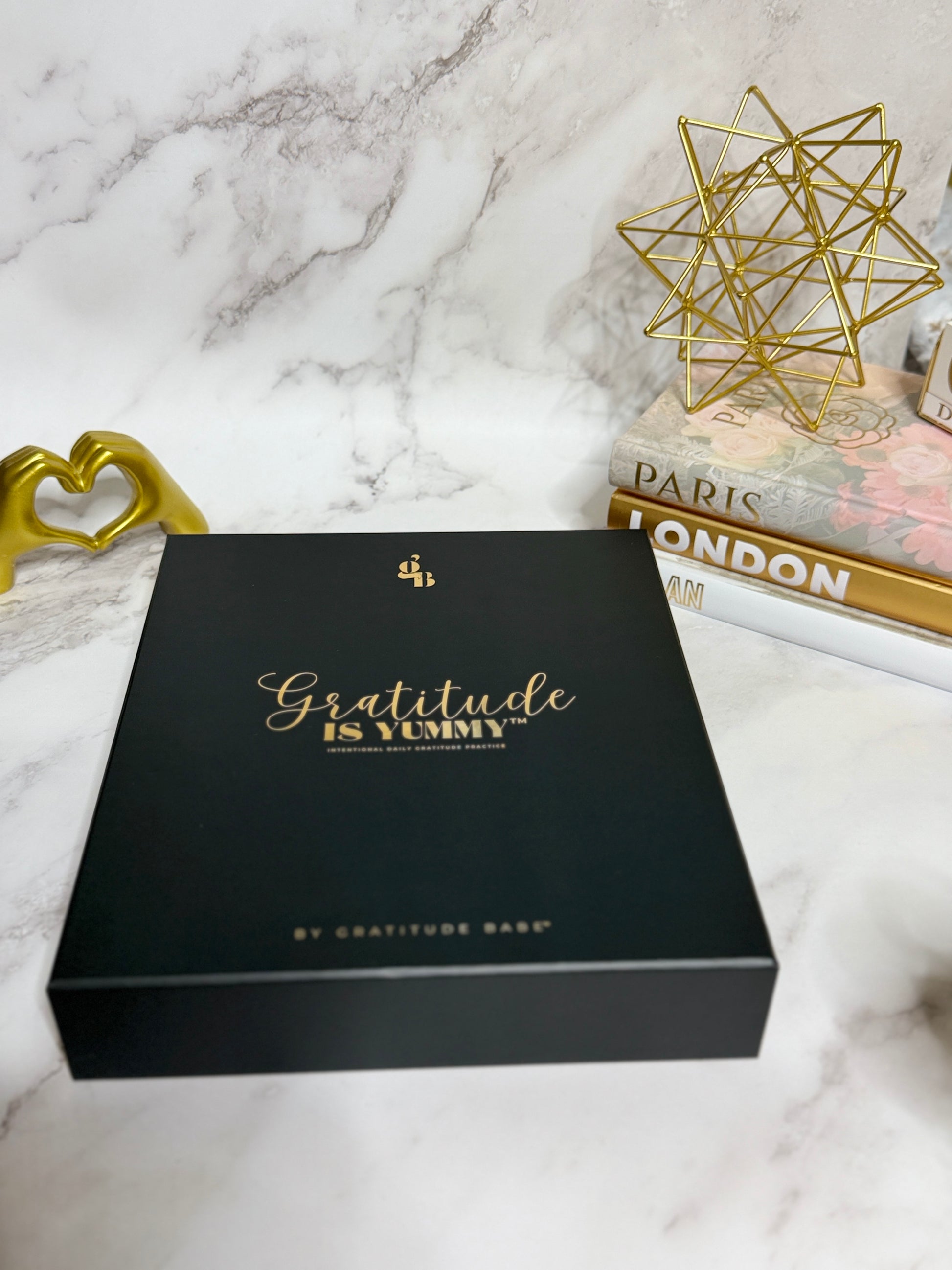 Black box with 'Gratitude is Yummy' text on a marble surface with decorative items.