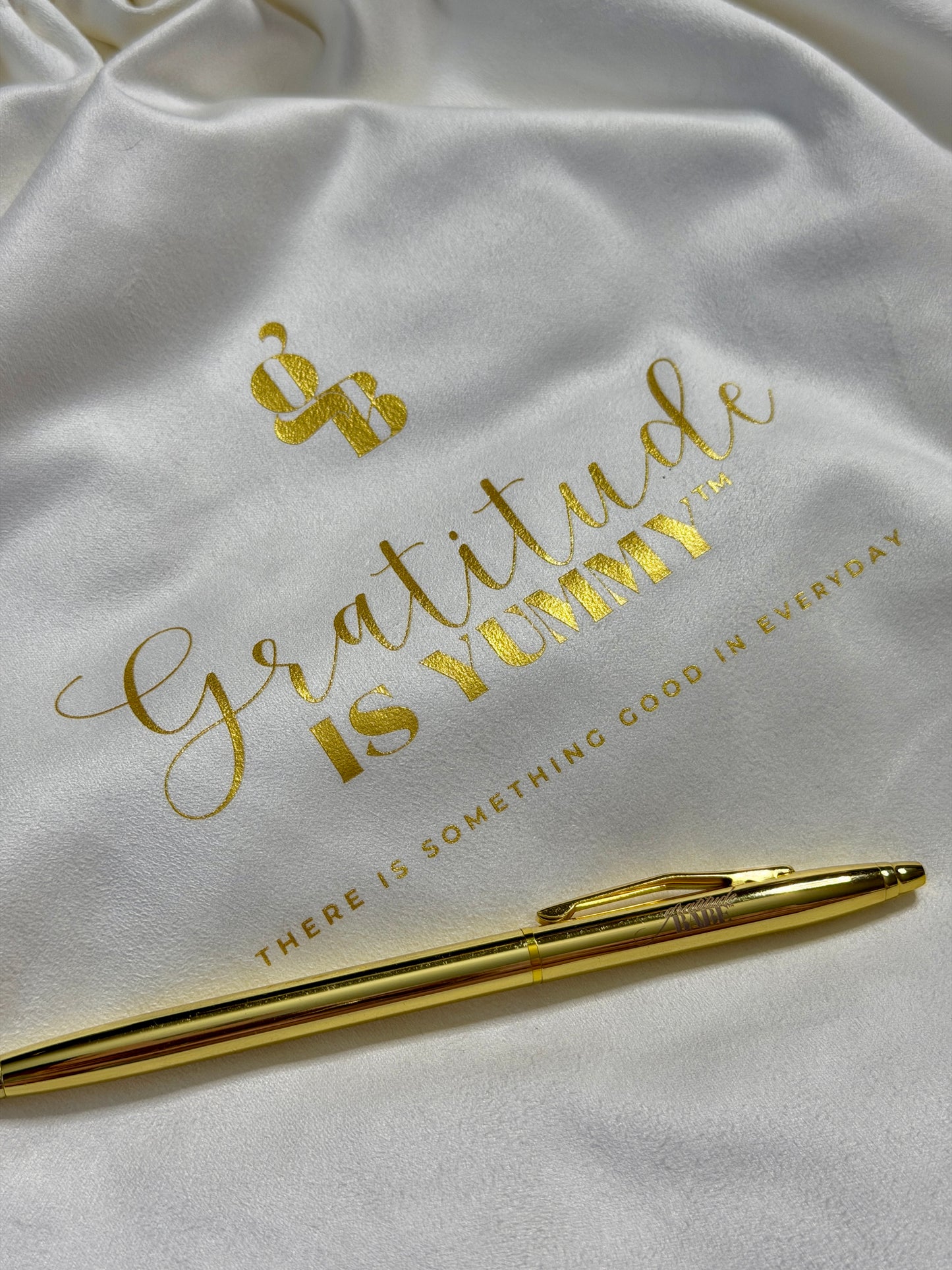 White bag with gold text and a gold pen on a white background