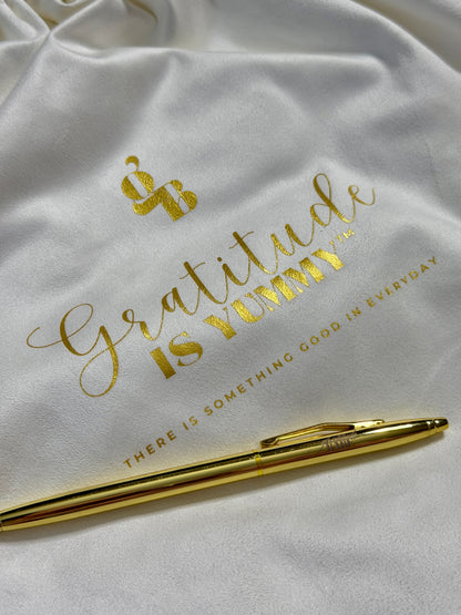 White bag with gold text and a gold pen on a white background
