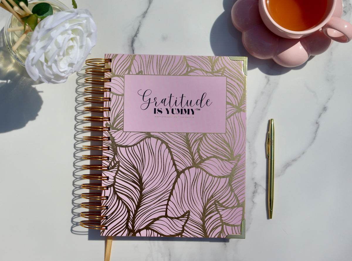 Blush pink Gratitude is Yummy Journal with gold spiral binding, tea, and Gratitude Babe pen for a five-minute daily gratitude ritual