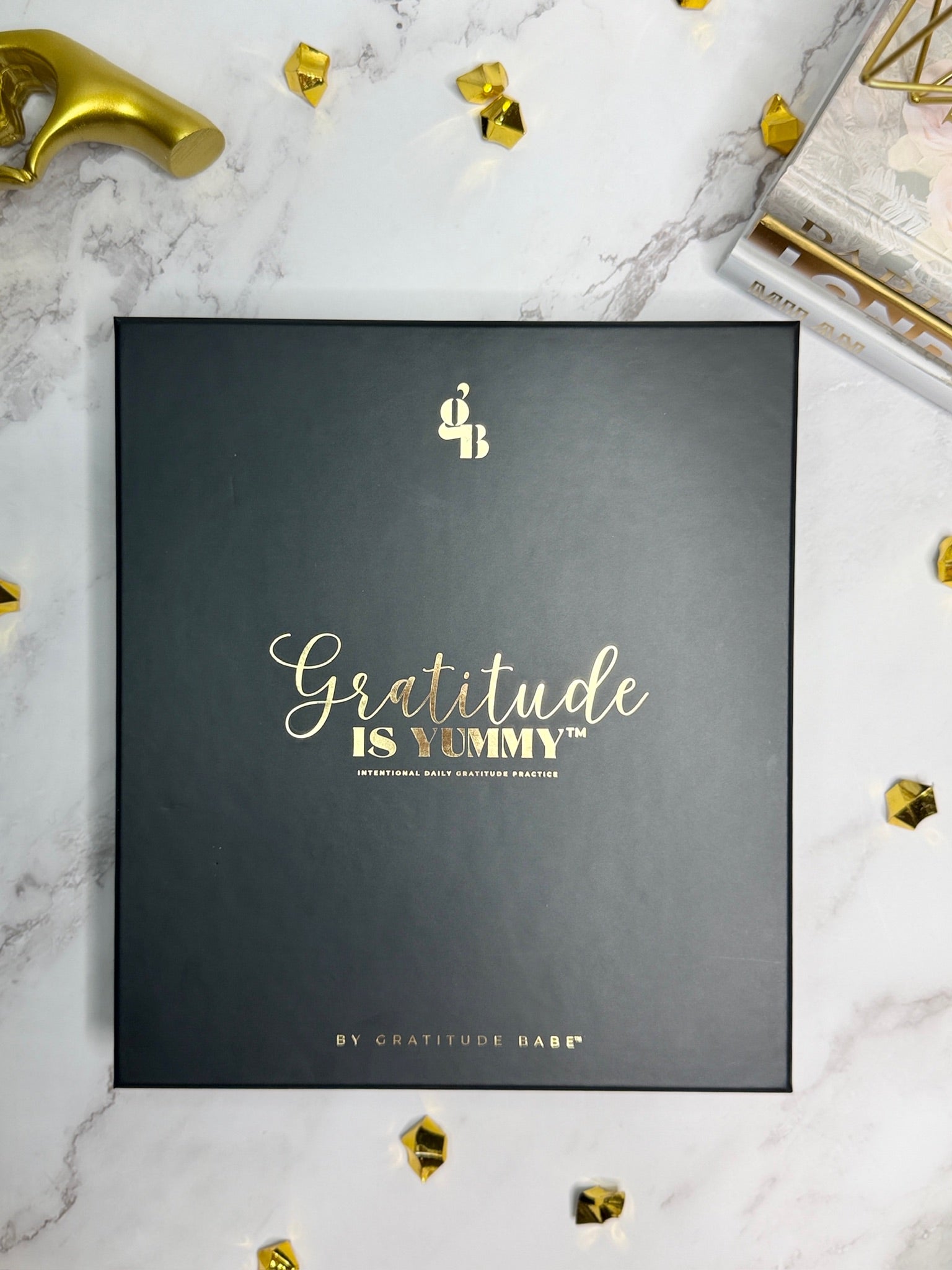Black box with 'Gratitude is Yummy' text on a marble surface with decorative elements.